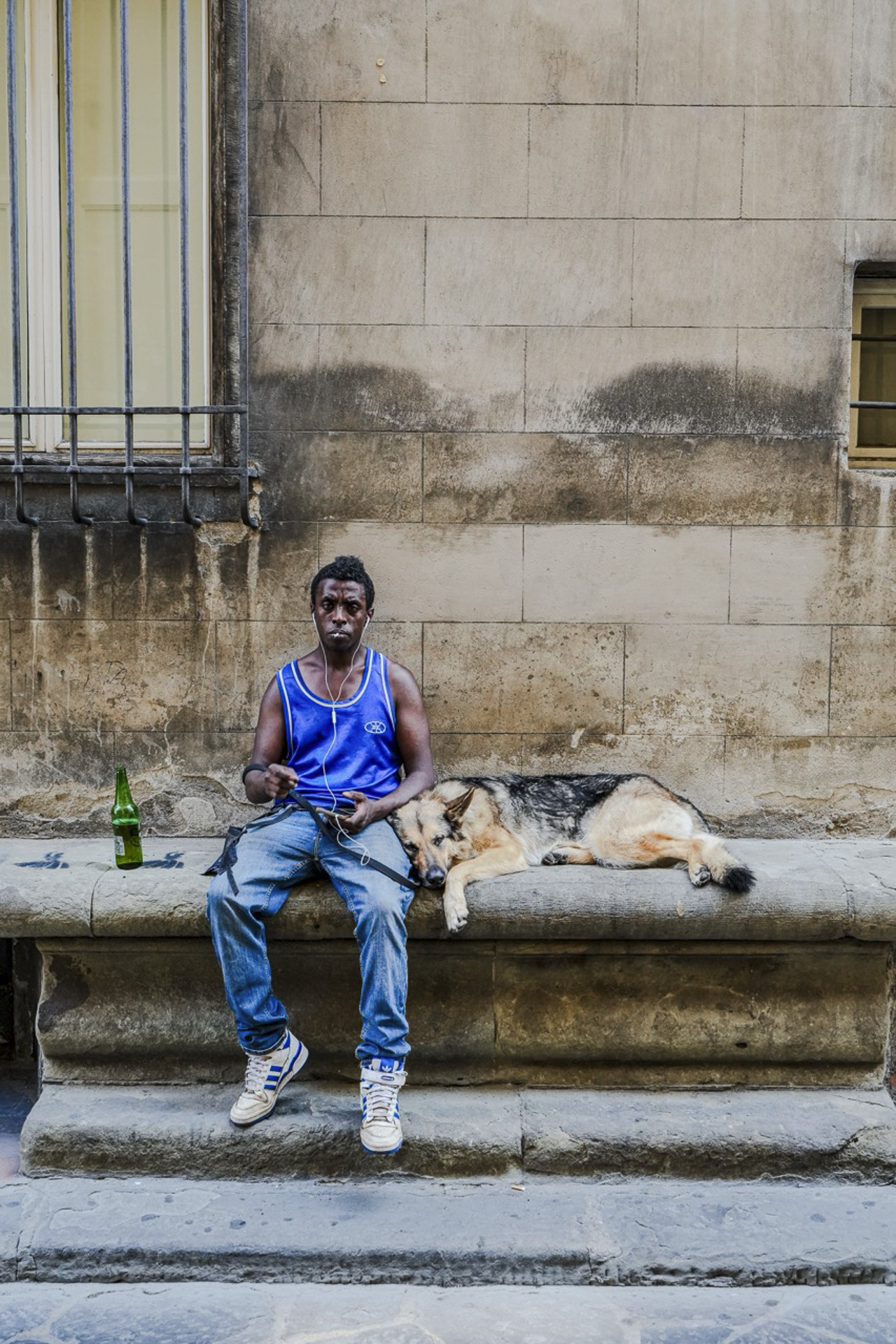 a young man seated on stone steps in florence, italy, with a dog resting beside him. shot in black and white.